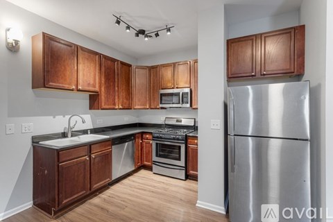 A kitchen with wooden cabinets and a stainless steel refrigerator.