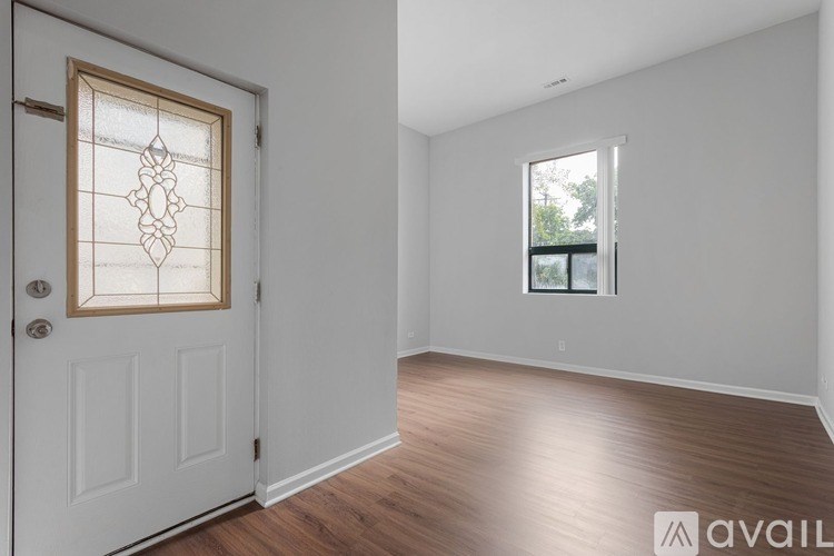 A room with a white door and a window with a view of trees.
