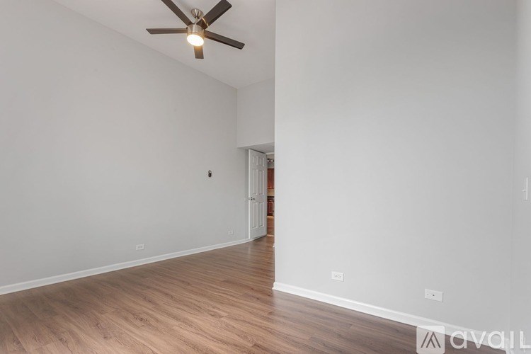 A room with a ceiling fan and wooden flooring.