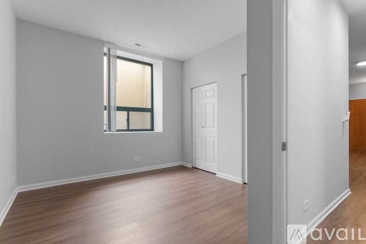 A spacious room with wooden flooring and a large window.