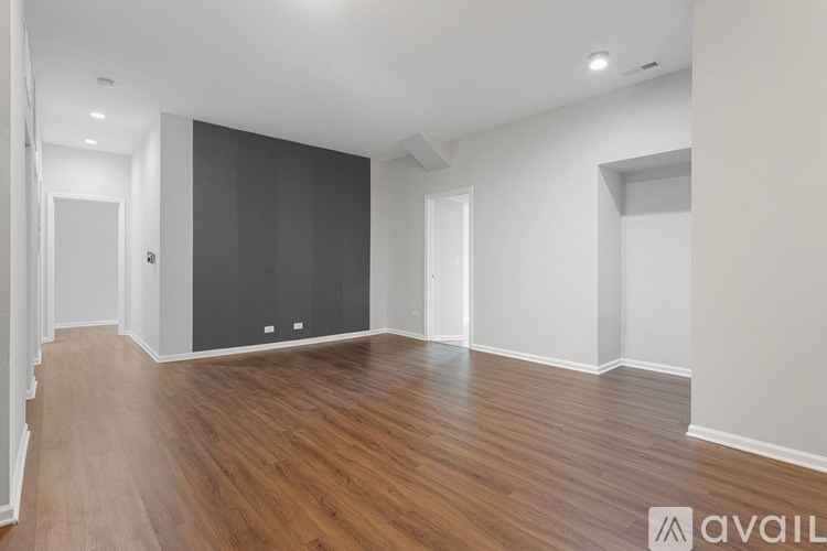 A spacious room with wooden flooring and white walls.