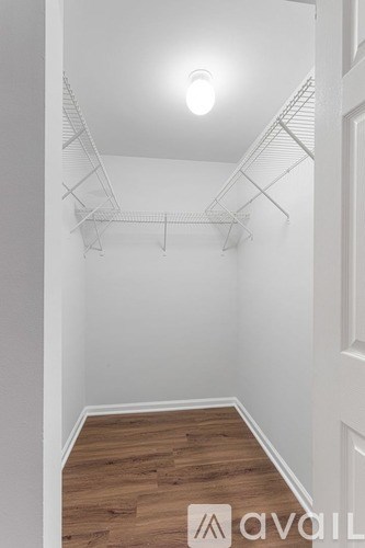 A white room with a light on the ceiling and a wooden floor.