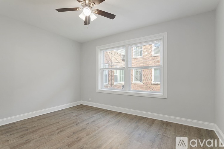 A room with a ceiling fan and a window overlooking a brick building.