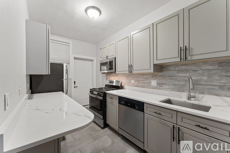 A kitchen with a white counter top and grey cabinets.