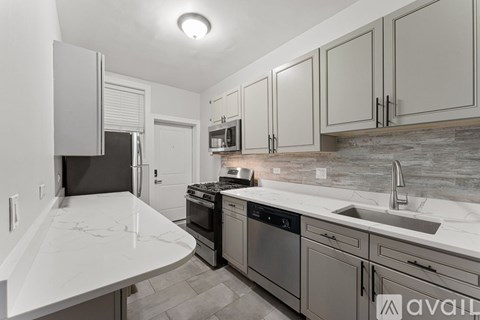 A kitchen with a white counter top and grey cabinets.