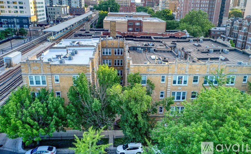 A view of a cityscape with a large building in the foreground and a train track running through the middle.