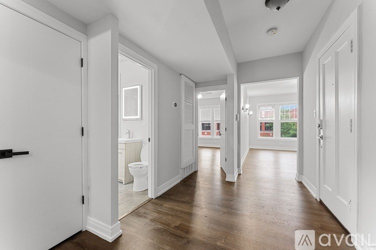 A long hallway with white doors and a wooden floor.