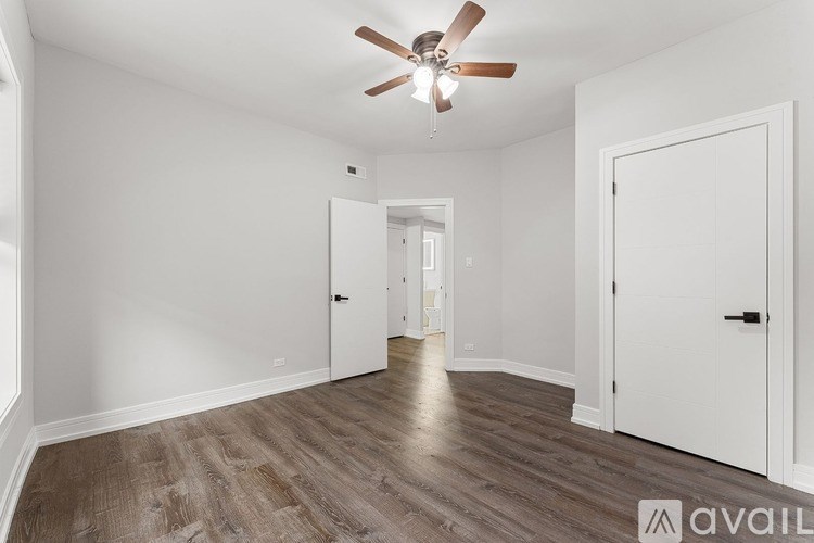 A room with a ceiling fan and wooden flooring.