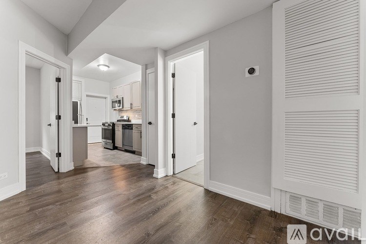 A modern kitchen with white cabinets and a wooden floor.