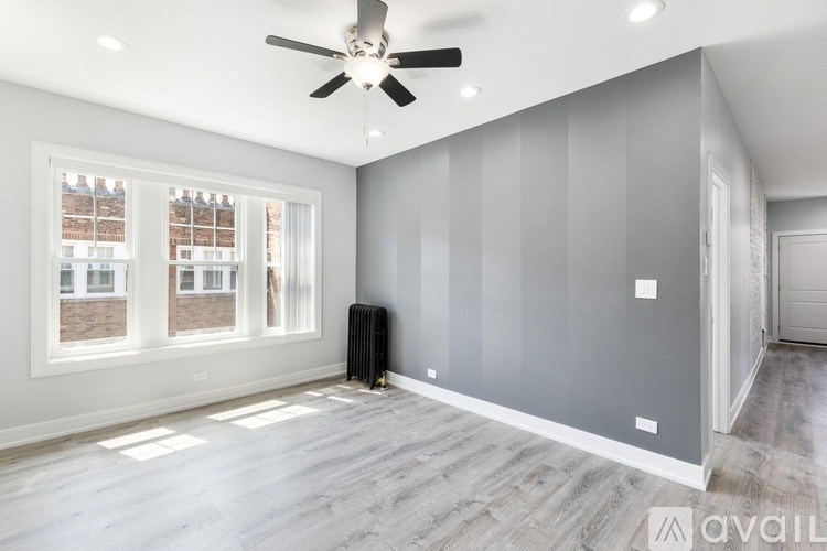 A spacious room with a ceiling fan and a radiator on the floor.