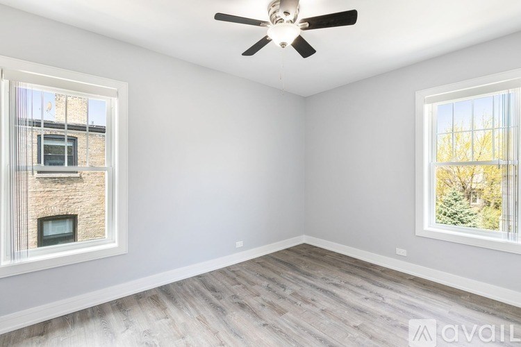 A room with a ceiling fan and two windows.