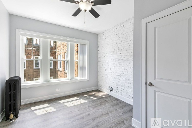 A room with a ceiling fan and a window showing a view of a building outside.