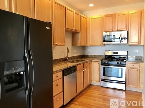 A kitchen with wooden cabinets and a black refrigerator.