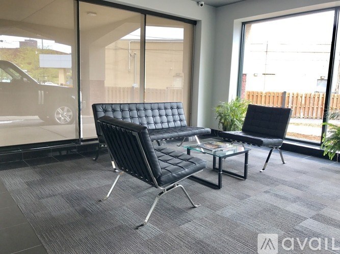 A black sofa and chair are in a room with a glass door.