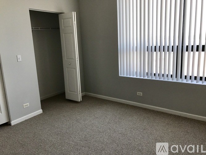 A room with a grey carpet, a white door and a white closet.