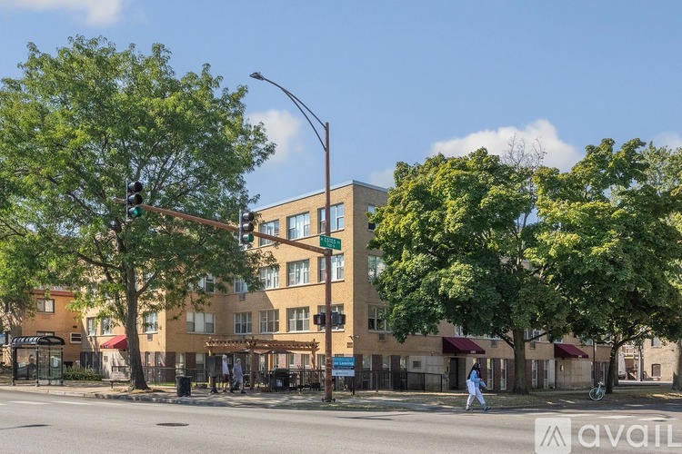 A person is crossing the street in front of a building with a green awning.