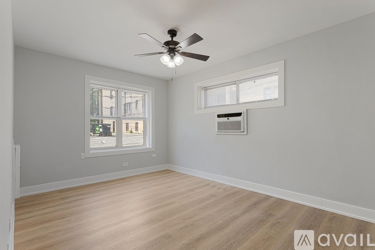 A room with a ceiling fan and two windows.