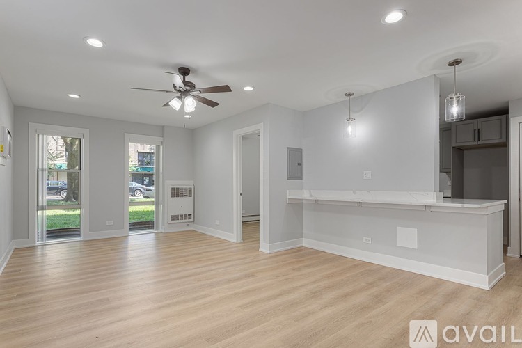 A spacious room with a ceiling fan and pendant lights.