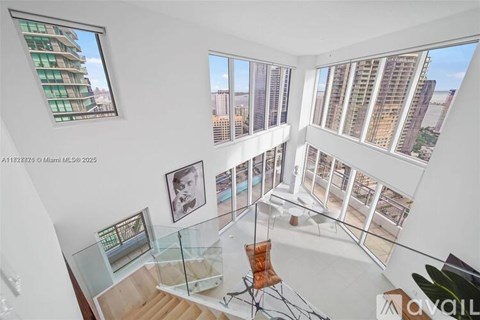 A balcony with a glass table and chairs overlooks a cityscape.