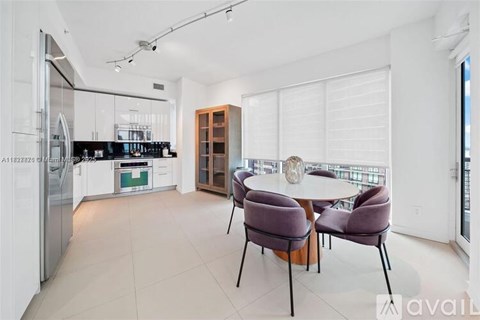 A modern kitchen with a dining table set for two.