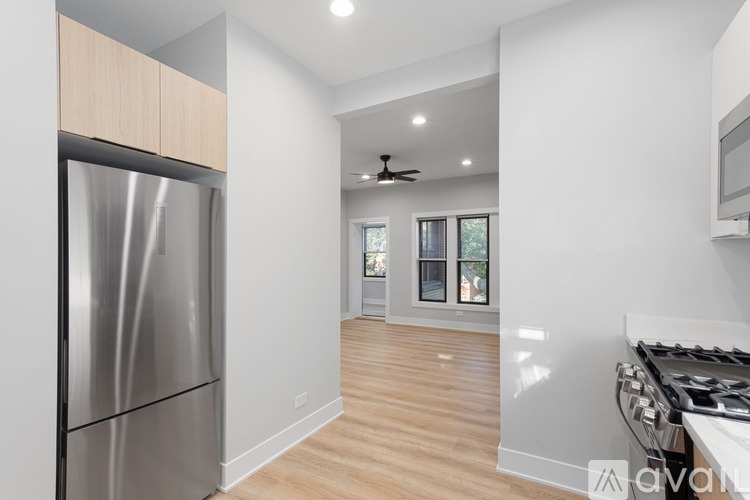 A modern kitchen with a stainless steel refrigerator and wooden flooring.