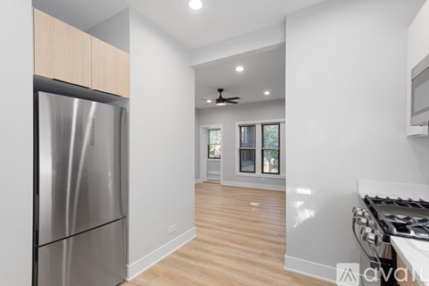 A modern kitchen with a stainless steel refrigerator and wooden flooring.