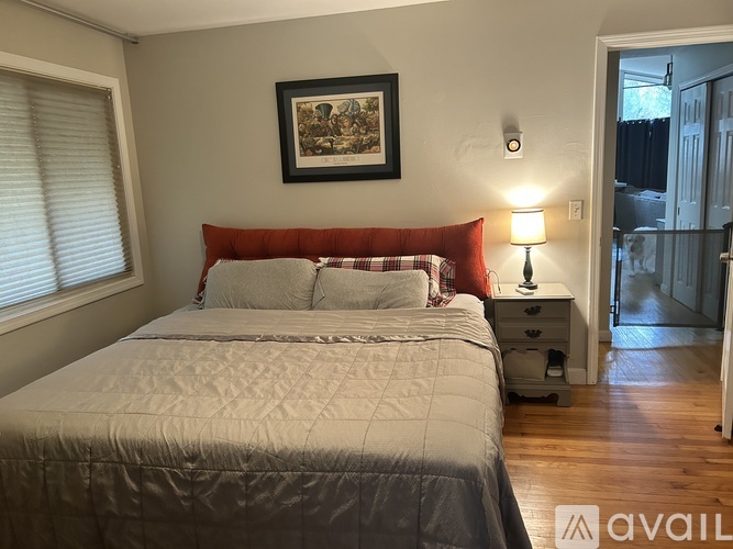 A bedroom with a large bed and a framed picture on the wall.