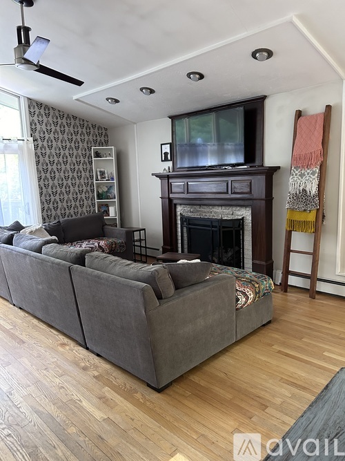A living room with a grey couch and a fireplace.