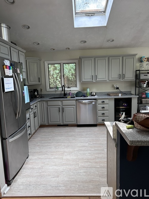 A kitchen with a refrigerator, sink, and cabinets.