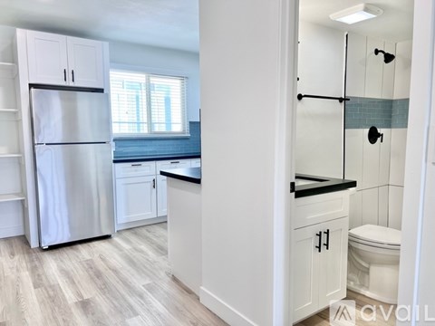 A kitchen with white cabinets and a refrigerator.