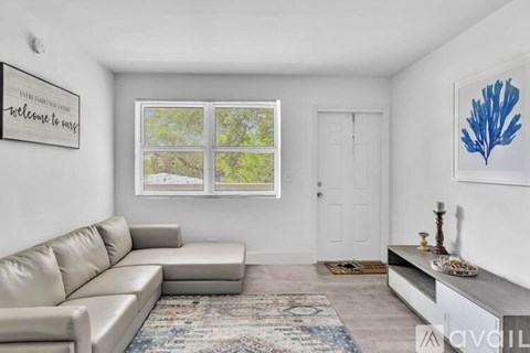 A living room with a grey sofa and a rug on the floor.