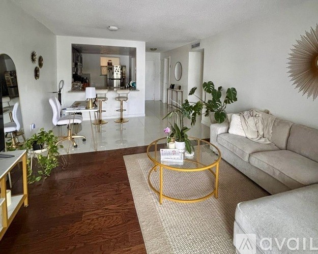 A living room with a white couch, a coffee table, and a dining table with chairs.