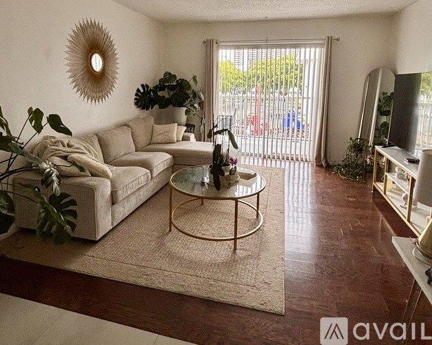 A living room with a beige sofa, a glass coffee table, and a mirror on the wall.