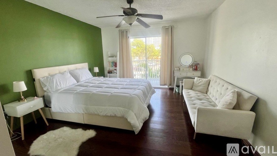 A bedroom with a white bed and a white couch.