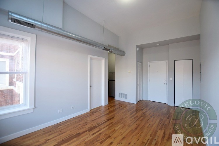 A room with wooden floors and white walls, with a window on the left side.