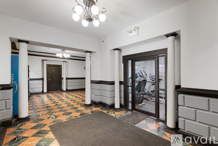 A hallway with a tiled floor and a chandelier hanging from the ceiling.