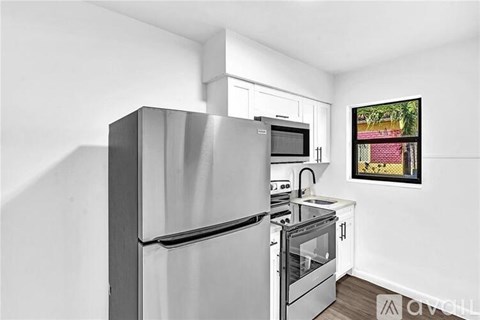 A modern kitchen with a refrigerator, microwave, oven, and stove.