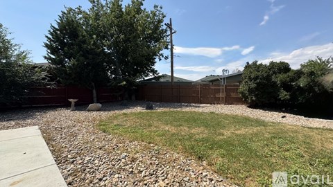 A backyard with a gravel area and a wooden fence.
