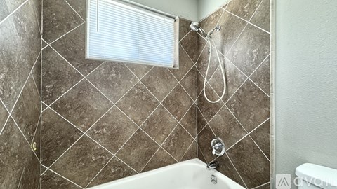 A tiled bathroom with a shower head and a window.