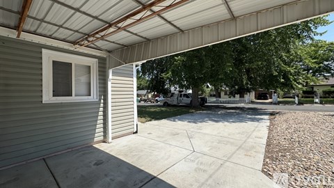 A patio area with a white metal roof and a concrete floor.