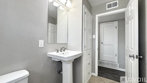 A white bathroom with a toilet, sink, and mirror.