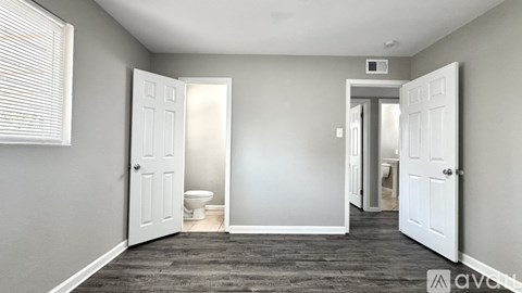 A room with a toilet and a door leading to another room.