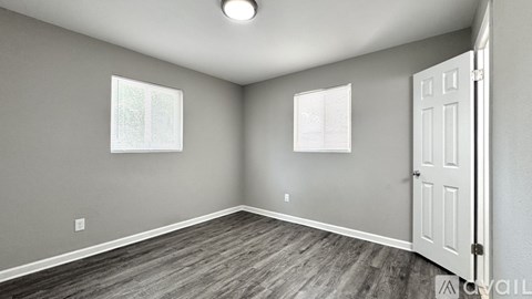 A room with a white door and two windows with blinds.