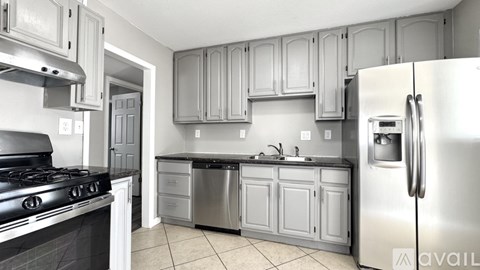 A kitchen with a stove, sink, and refrigerator.