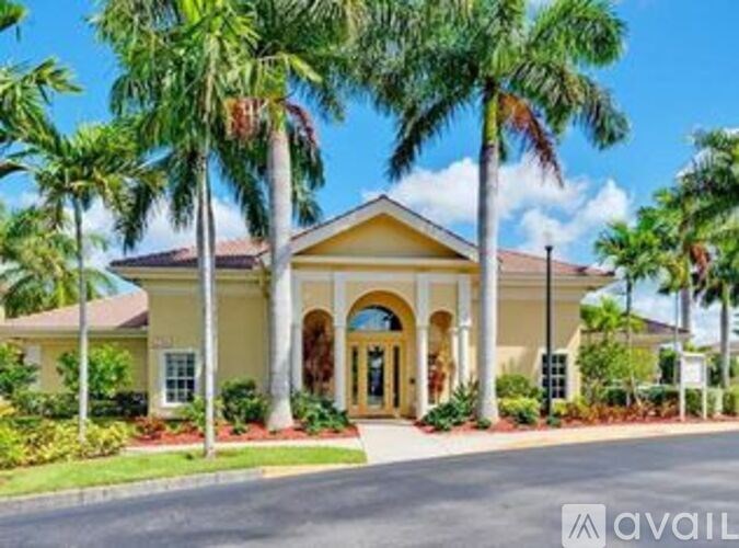 A house with a yellow front and palm trees in front.
