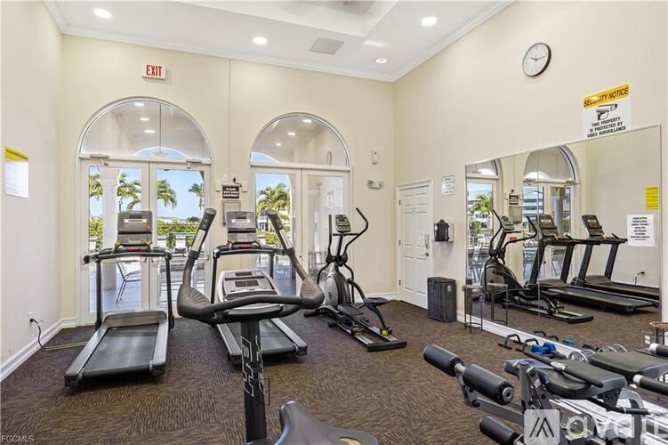 A gym with treadmills, exercise bikes, and a mirror.