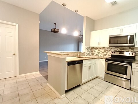 A kitchen with a white counter and stainless steel appliances.