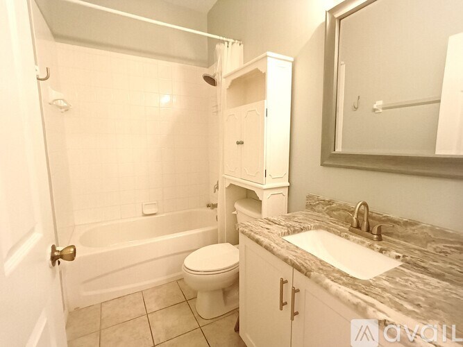 A white bathroom with a marble counter top and a white toilet.