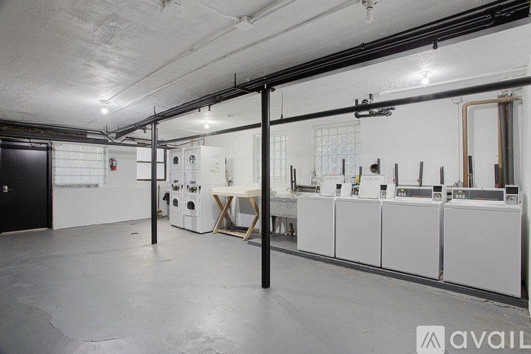 A spacious room with white tiled walls and a row of white appliances on the right side.