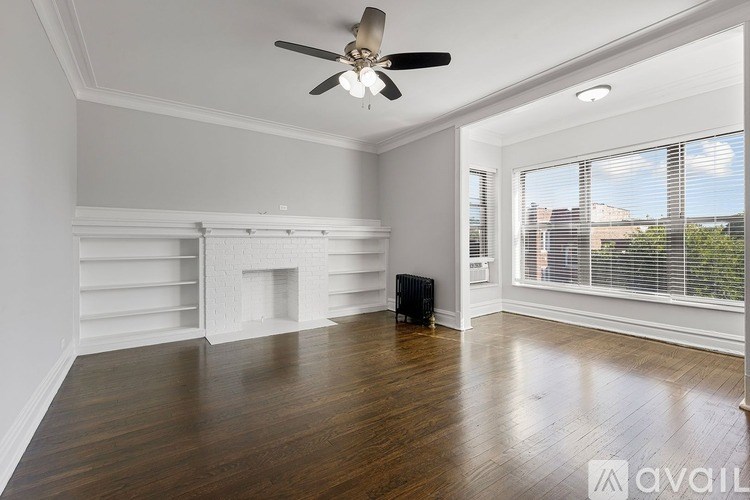 A room with a ceiling fan and wooden flooring.
